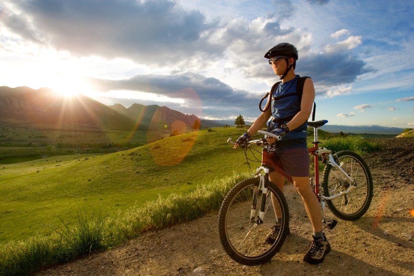 Man sitting on bick on dirt bike trail with landscape in background