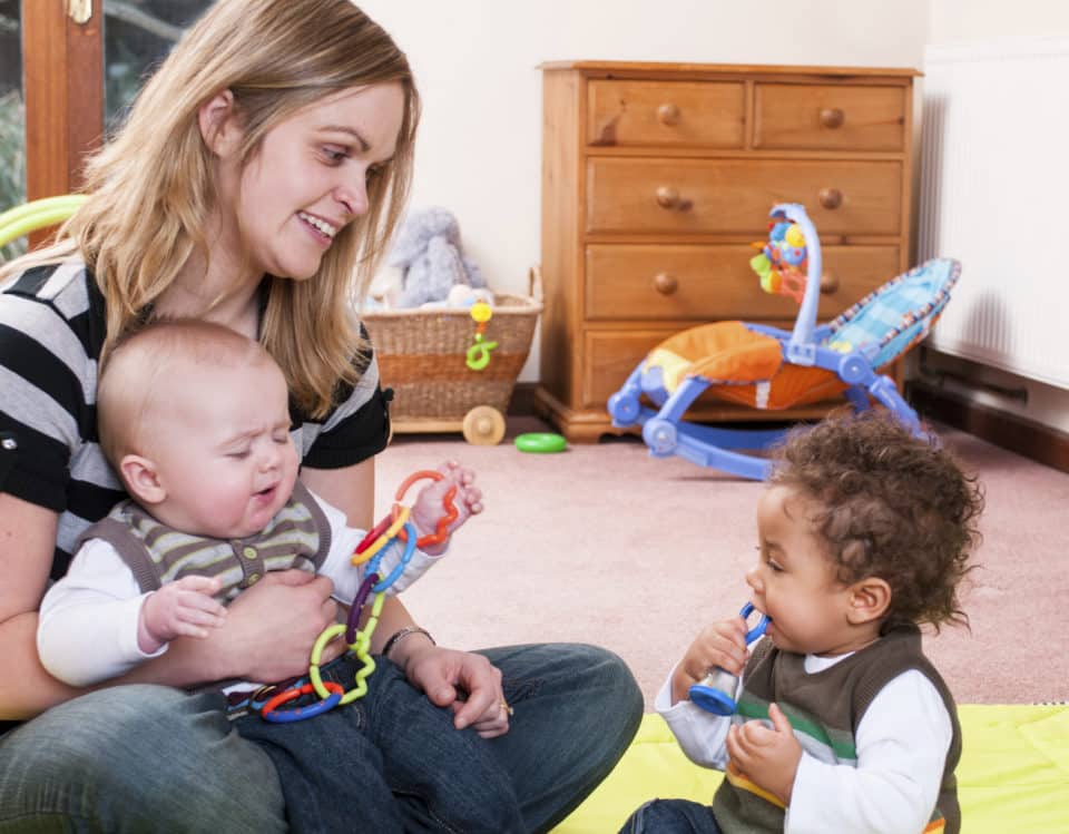 Young mother holding baby and playing with toddler